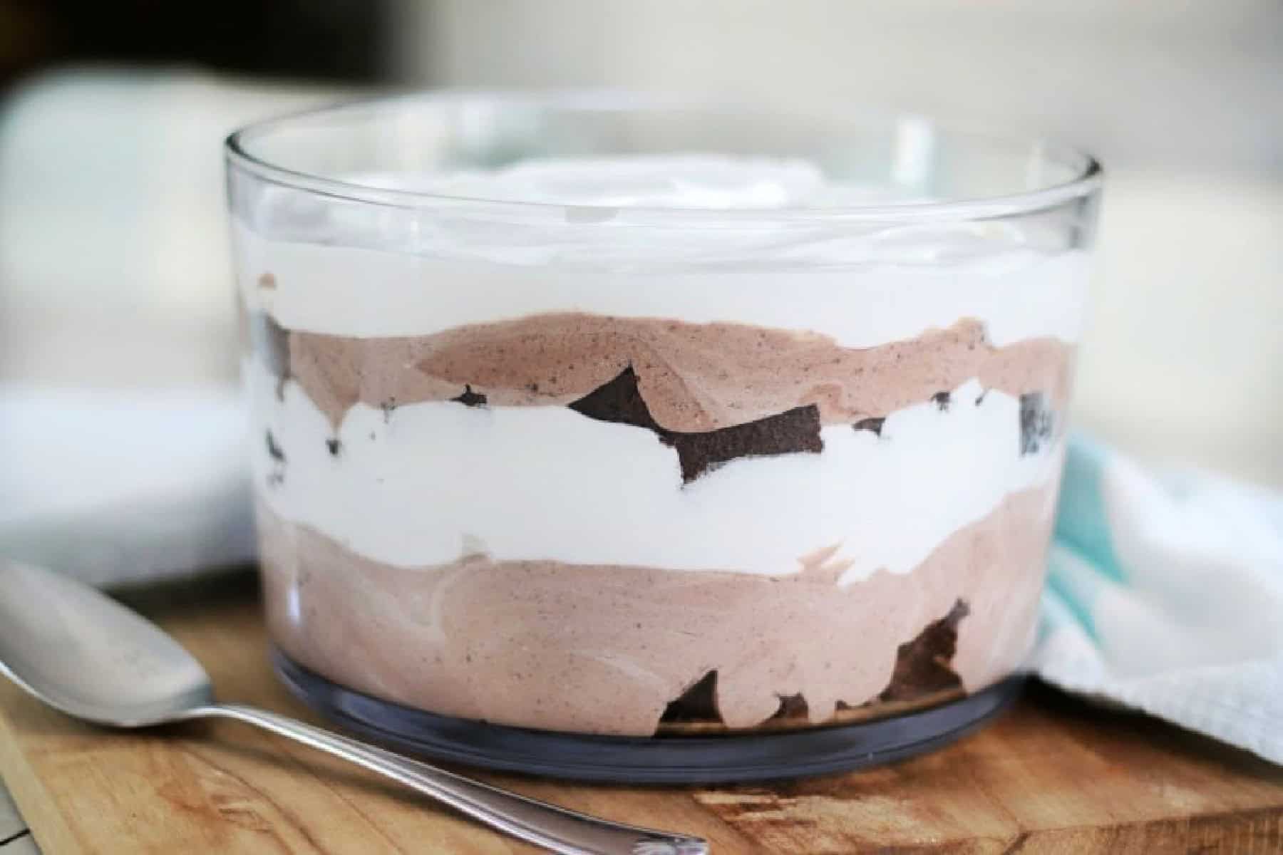 Glass trifle bowl layered with brownie, cream, and pudding.