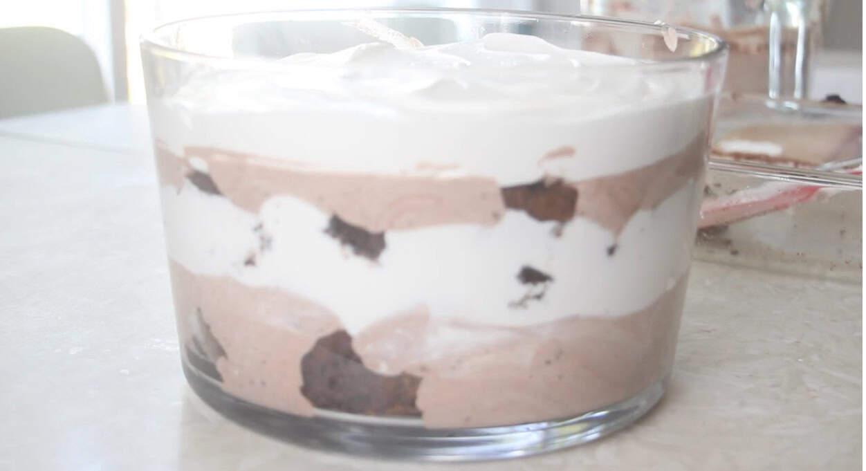 Glass trifle bowl layered with brownie, cream, and pudding.