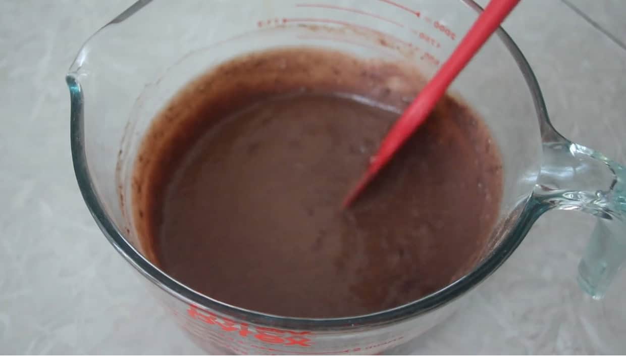 Glass bowl of pudding and sweetened condensed milk mixed with rubber spatula.