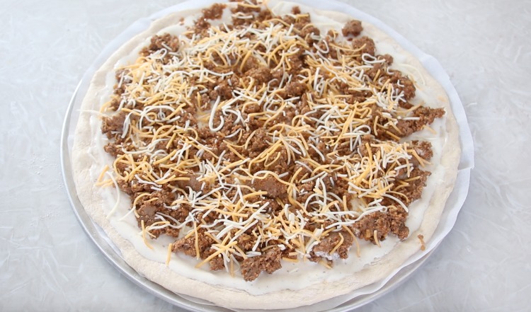 pizza dough with sauce meat and cheese