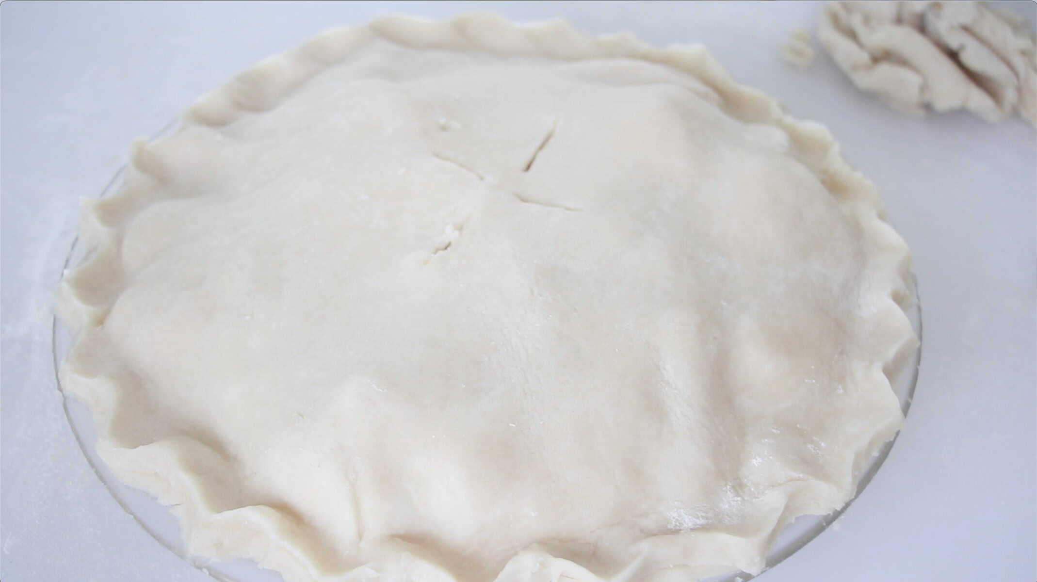 Unbaked peach pie on a cutting board.