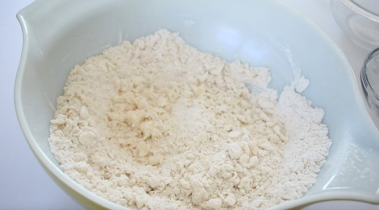 Large mixing bowl with flour and butter cut into coarse crumbs.