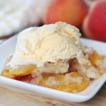serving of cobbler on white plate with scoop of vanilla ice cream