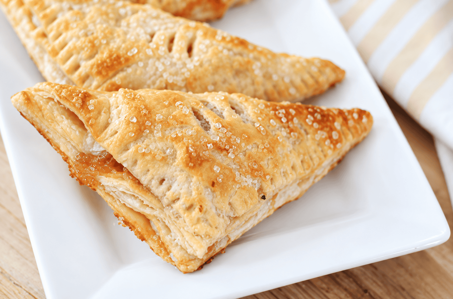 Two peach turnovers on a white plate.