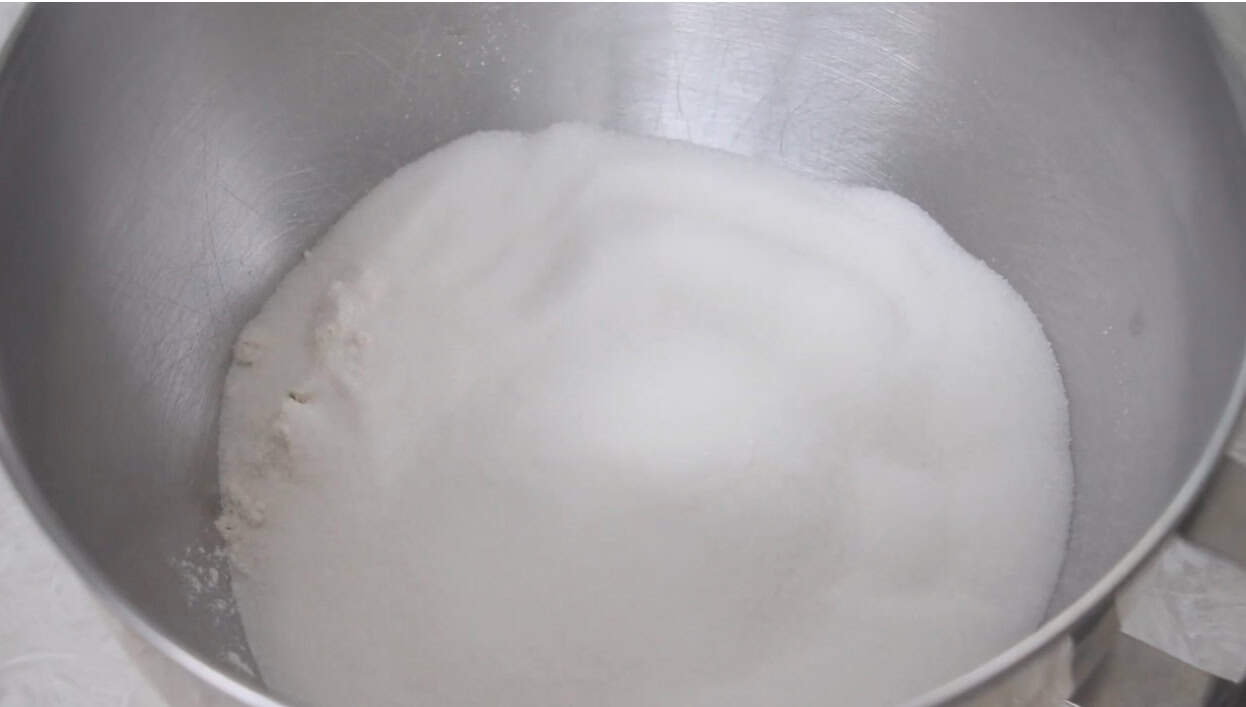 Mixing bowl with flour, sugar and salt inside.