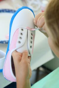 child painting shoes with acrylic paint