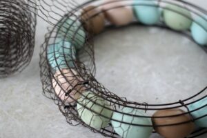 wooden eggs on wreath frame being wrapped in chicken wire