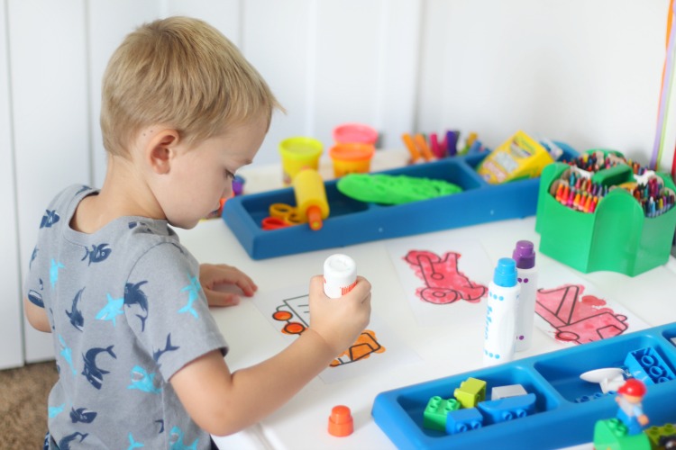 toddler sitting at art desk coloring a picture of a truck