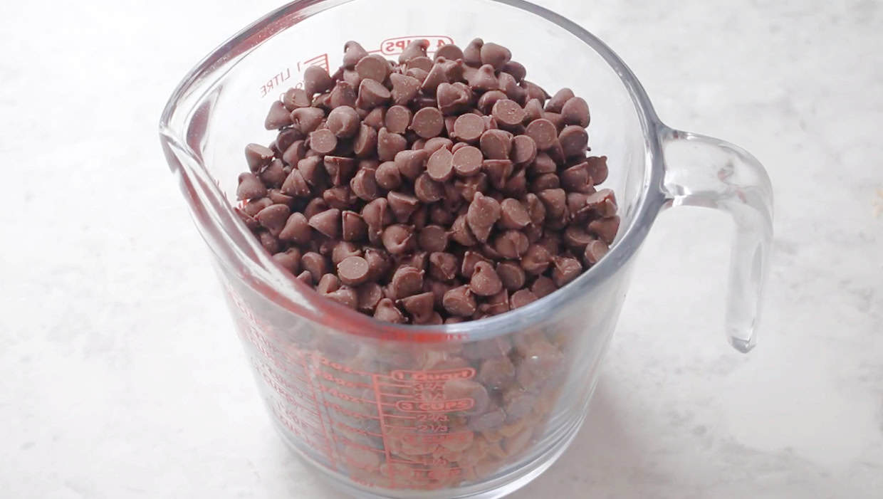 Large glass measuring cup with butterscotch chips and chocolate chips.