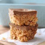 Two scotcheroos cut into squares and stacked on parchment paper.