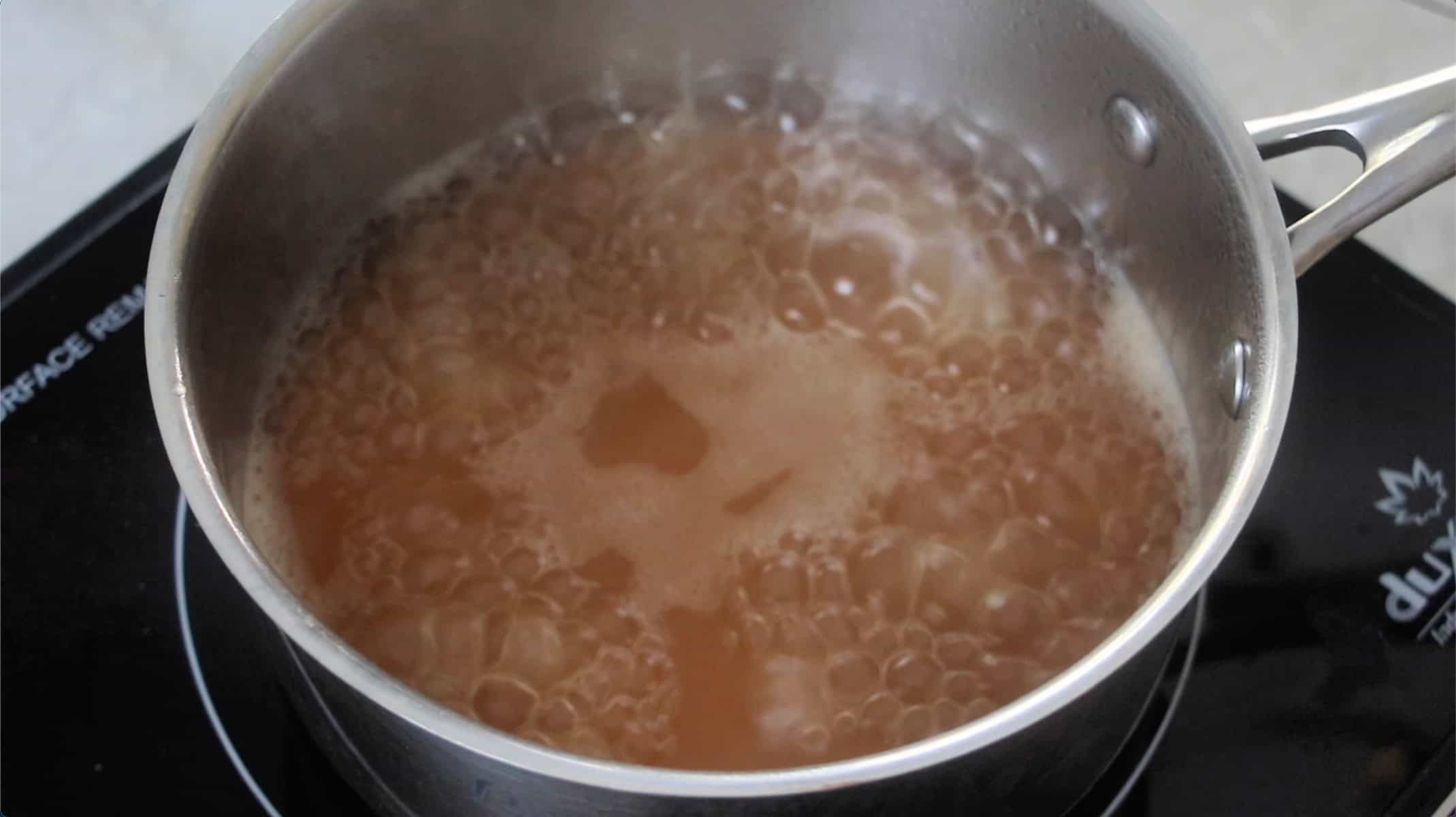 Pan of simmering apple cider on stove.