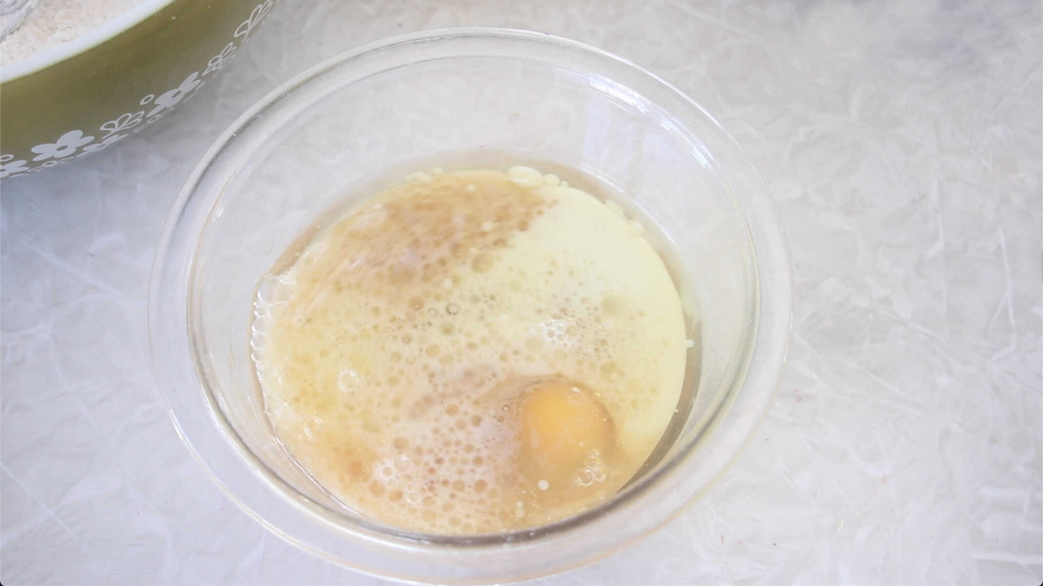 Glass bowl of milk, egg, cider, and oil.
