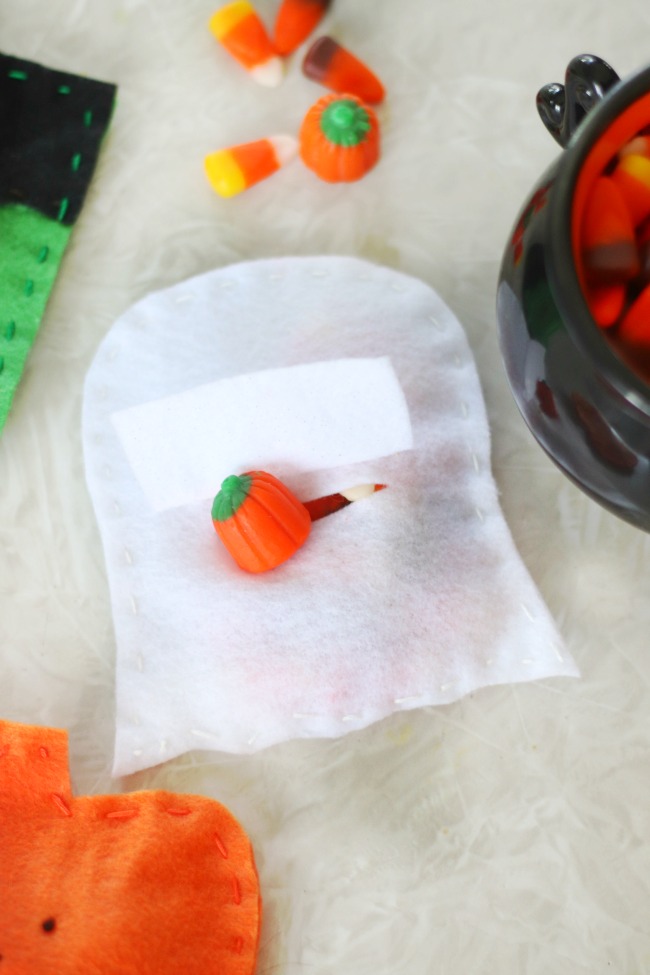 back of ghost candy pouch with candy pumpkin sticking out of slit