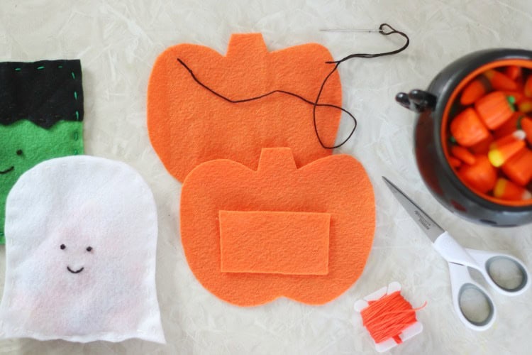 Two felt pumpkins next to scissors and string.