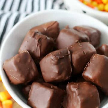 Homemade butterfingers in a white bowl next to a bowl of candy corn.