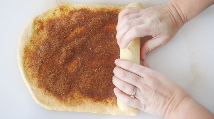 rolling up bread dough with cinnamon filling