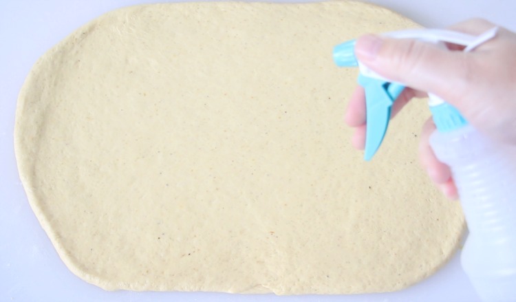 spray bottle spritzing dough with water