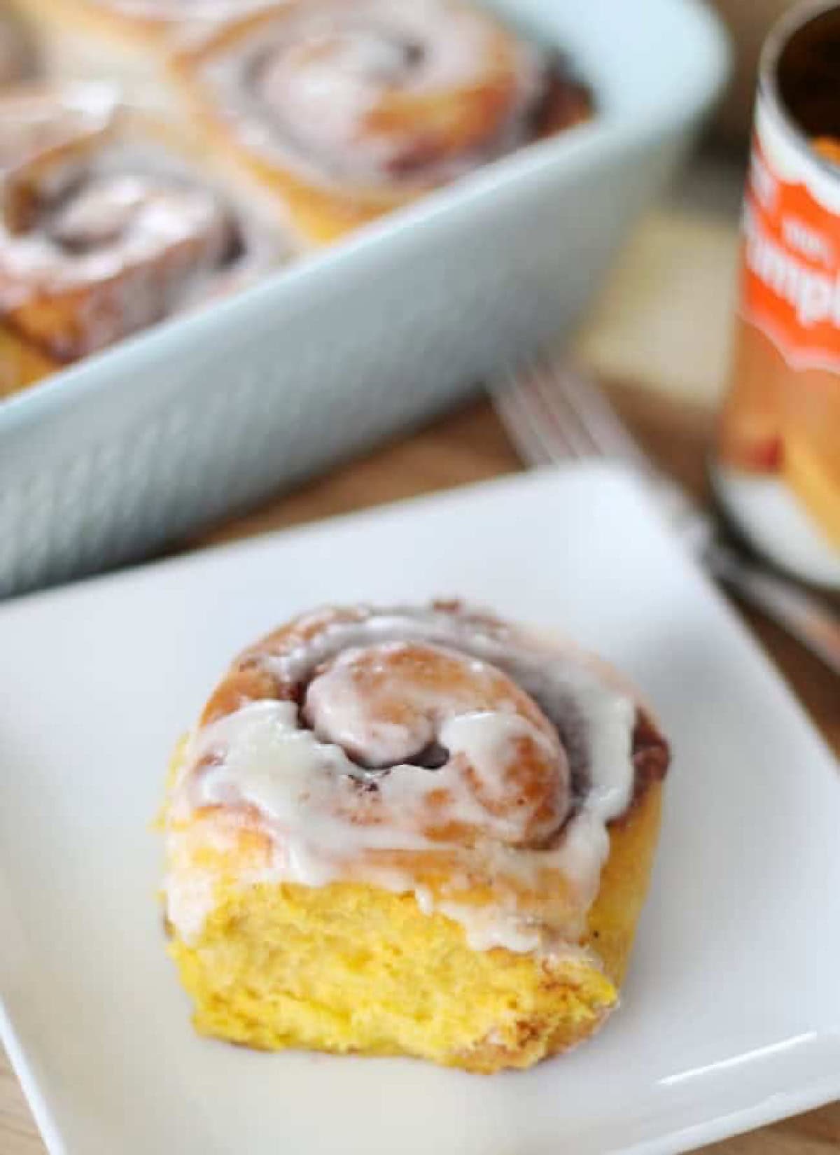 Pumpkin cinnamon roll on white plate.
