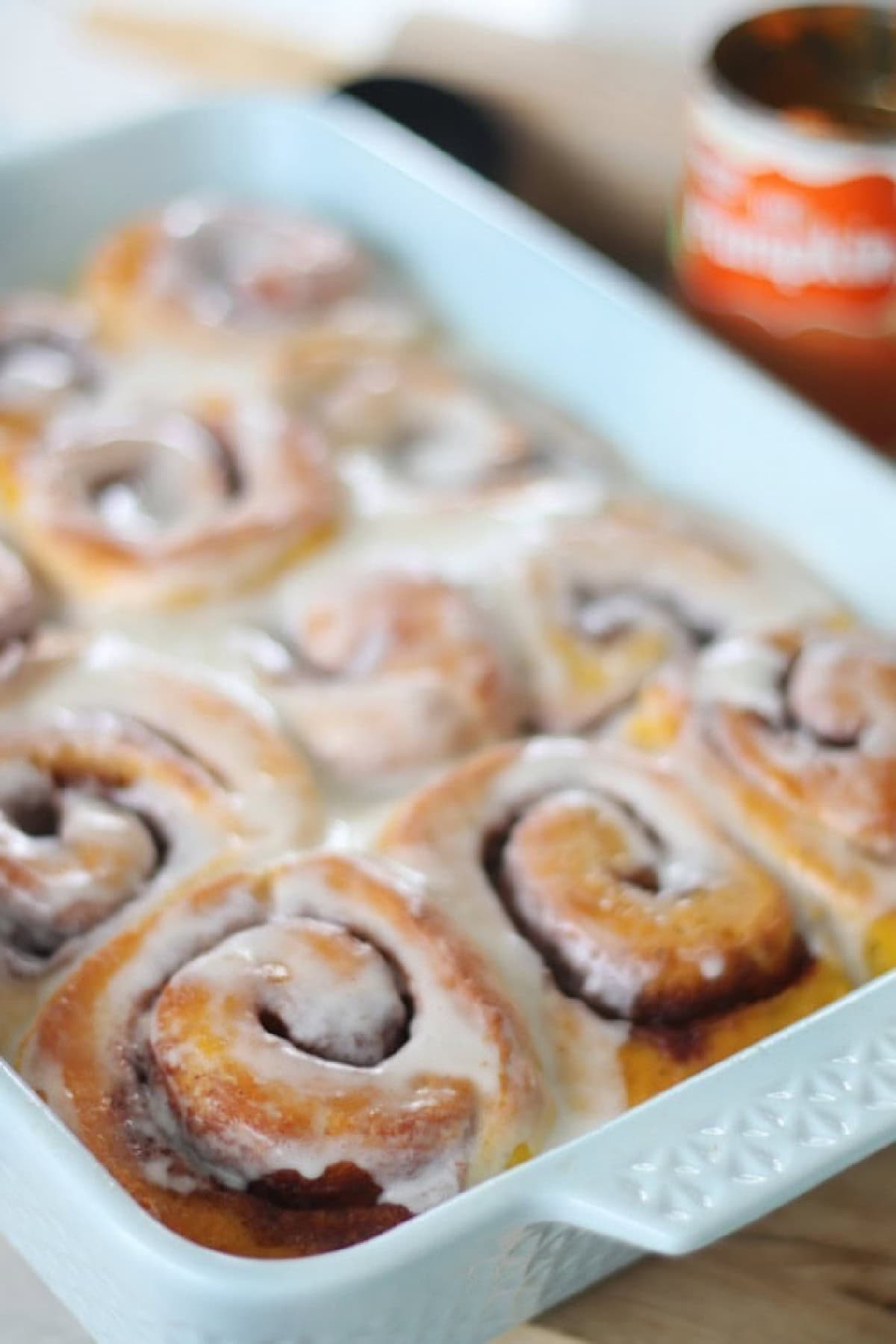 Baking dish with pumpkin cinnamon rolls frosted with buttercream.