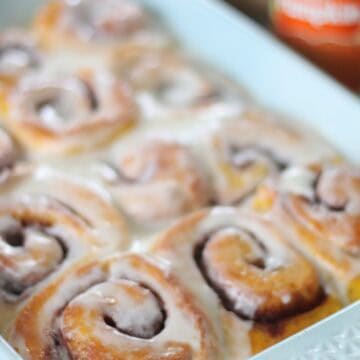 frosted pumpkin cinnamon rolls in baking dish