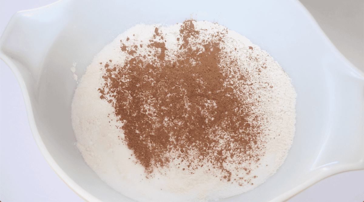 Large mixing bowl with flour, baking powder, salt, cinnamon, sugar and nutmeg.