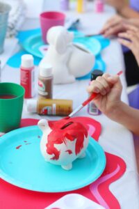 little boy painting a red piggy bank