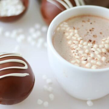 hot chocolate bomb next to white mug of hot chocolate