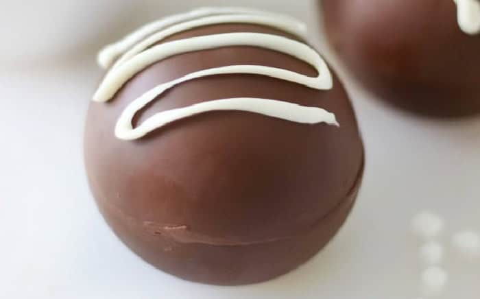 Hot cocoa bomb drizzled with white chocolate.