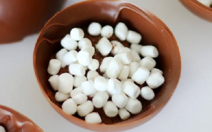 Half of a cocoa bomb filled with cocoa mix and marshmallows.