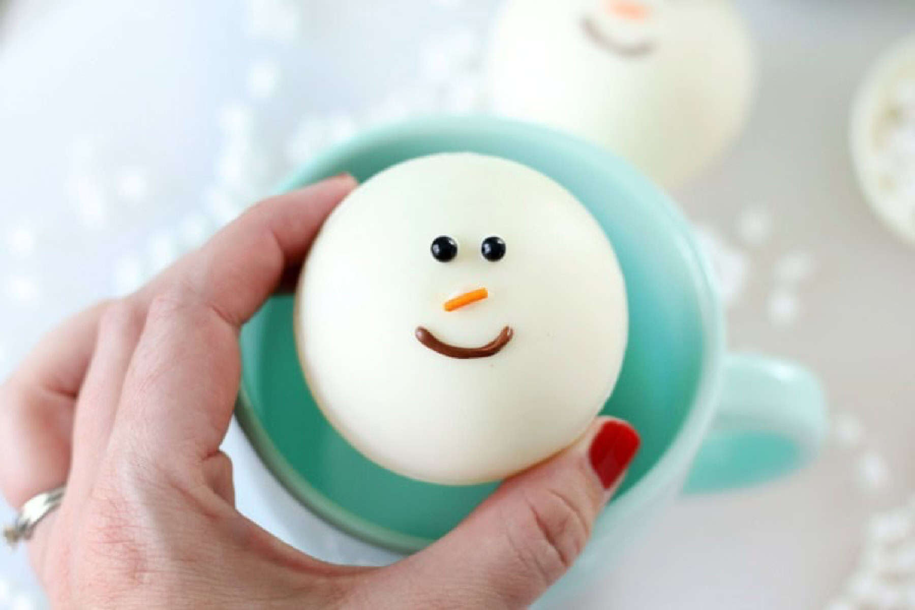 Hand holding snowman cocoa bomb.