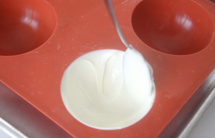 spoon smoothing out melted white chocolate in chocolate mold