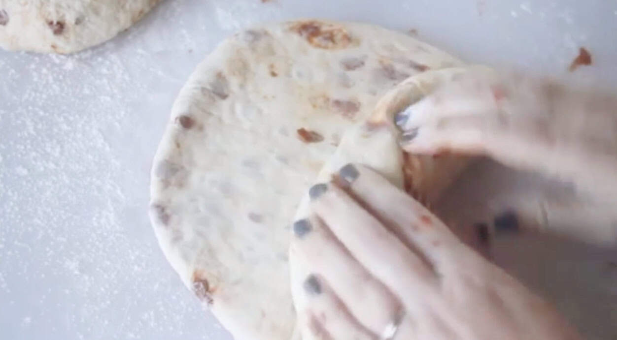 Hands rolling dough into loaf shape.