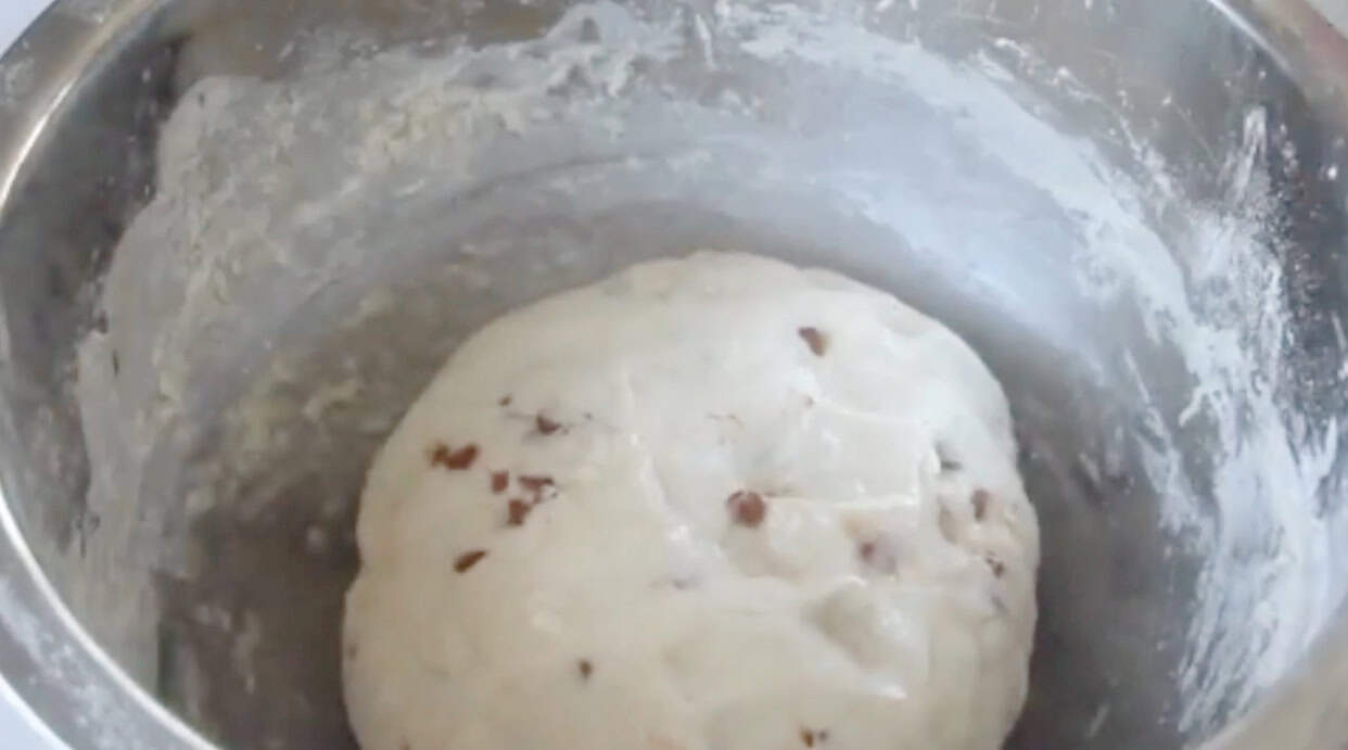 Metal mixing bowl with cinnamon chip bread dough rising.