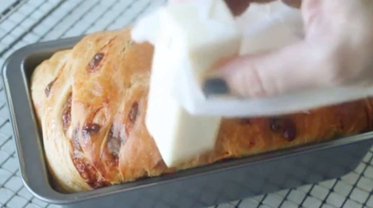 Butter spread over loaf of hot cinnamon chip bread.