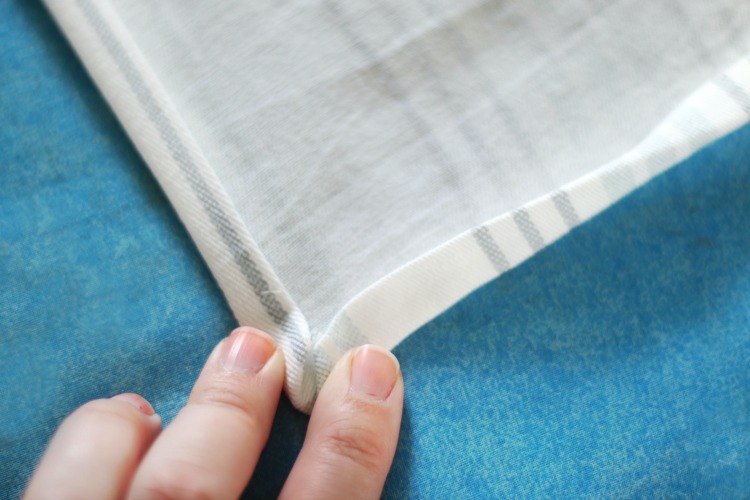 finger holding corner on cloth napkin hem