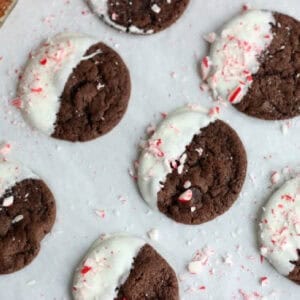 Triple chocolate cookies dipped in white chocolate on parchment paper.