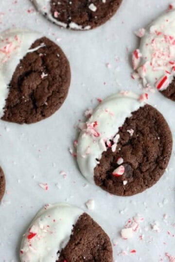 Triple chocolate cookies dipped in white chocolate on parchment paper.