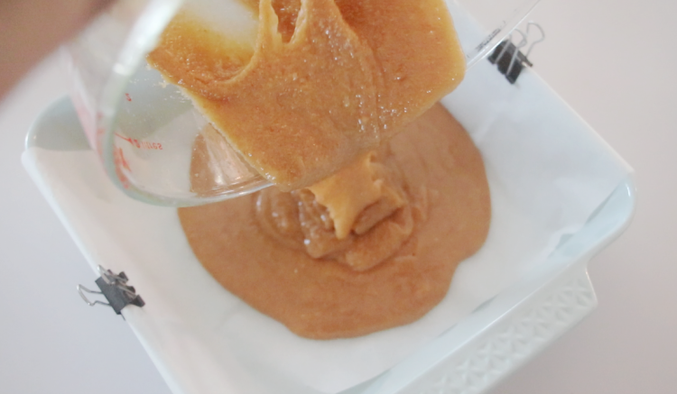 hot caramel mixture being poured into baking dish