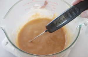 candy thermometer dipped into hot caramel mixture