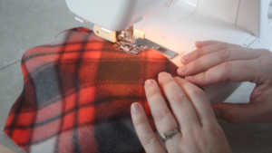 hands feeding fleece fabric through sewing machine