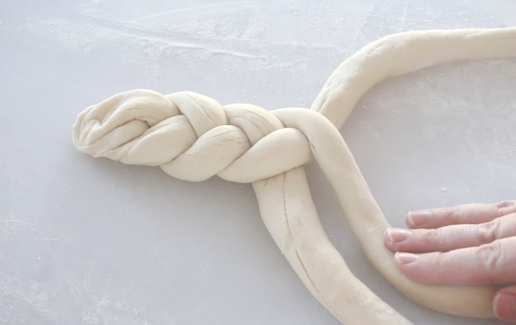 hands braided 3 strips of pretzel dough