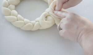 hand placing dough bow on pretzel wreath