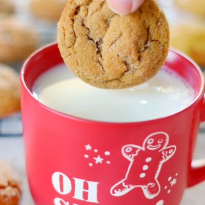hand dipping ginger cookie in milk