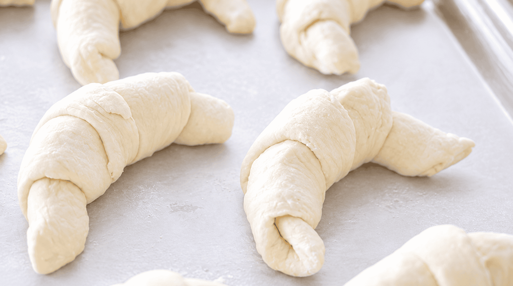 Baking sheet with unbaked croissants.