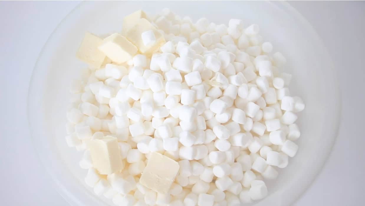 Plastic bowl with mini marshmallows and butter.