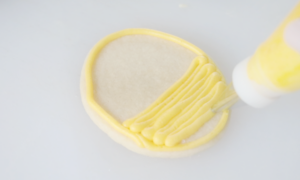 egg shaped sugar cookie outlined in yellow buttercream frosting