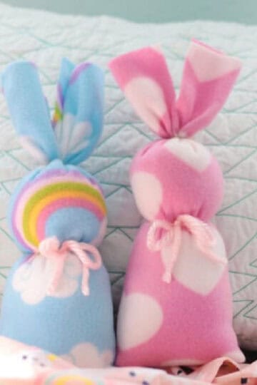 Two fleece bunnies placed against a pillow.