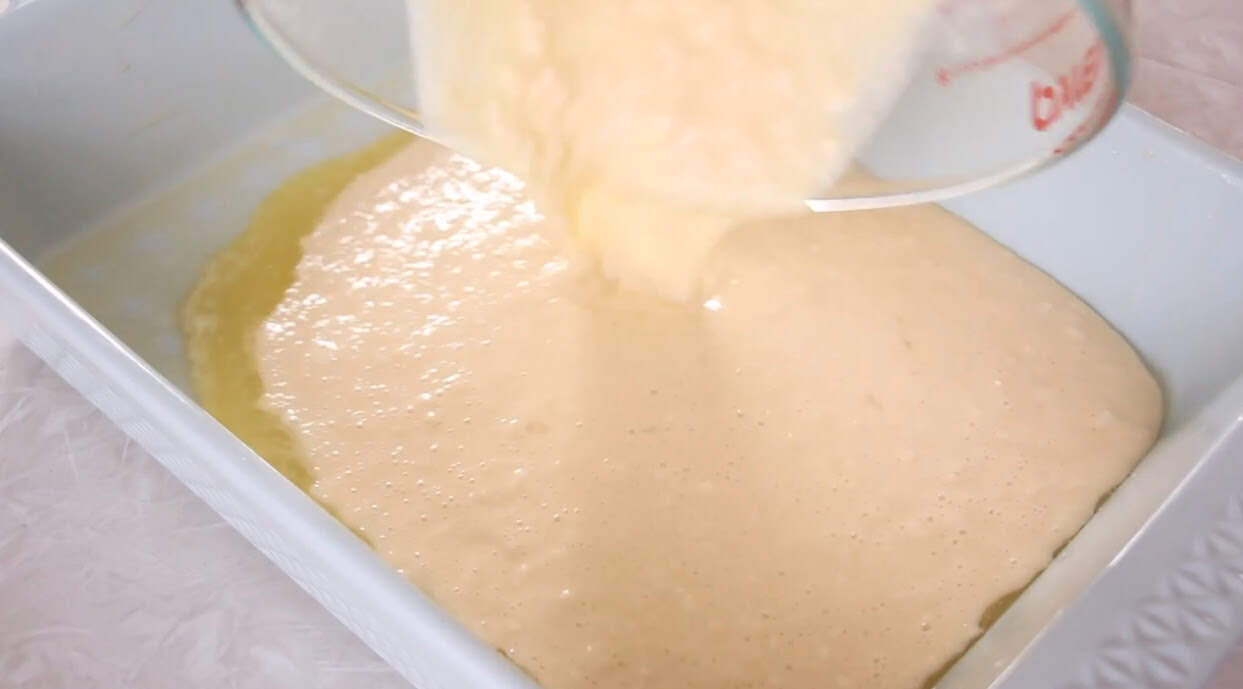 German pancake batter poured into hot baking dish with butter.