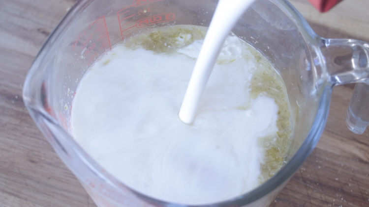 heavy whipping cream being poured into glass measuring cup