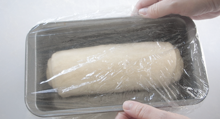 croissant bread dough in loaf pan covered in plastic wrap